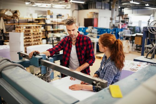 Experienced worker supervising his apprentice in printing factory