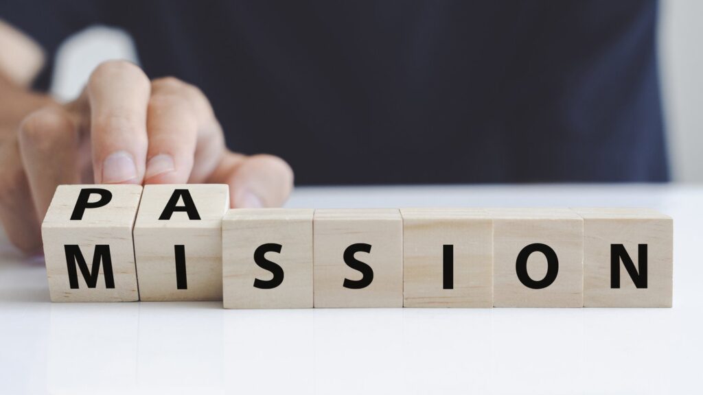 Hand of a man who turning a wooden block with the word passion and mission. Hand turns wooden block and changes the name "mission" to "passion".